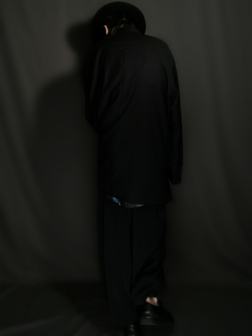 ブラック系のテーラードジャケット、ブラック系のスカート、ブラック系のドレスシューズを着用したメンズの冬コーディネートの4枚目の写真