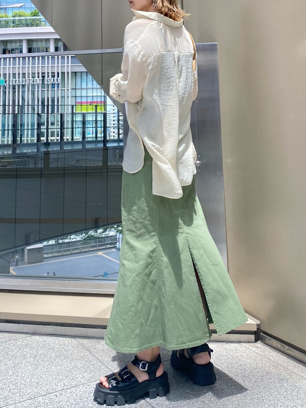 ブラウン系のショルダーバッグ、グリーン系のデニムスカート、ホワイト系のシャツ/ブラウスを着用したレディースの夏コーディネートの2枚目の写真