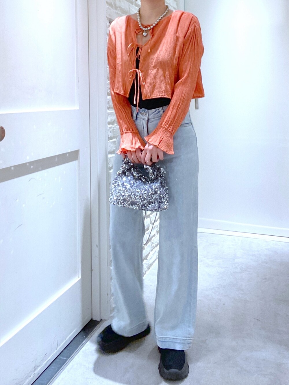 ブルー系のデニムパンツ、ブラック系のブーツ、オレンジ系のシャツ/ブラウスを着用したレディースの春コーディネートの2枚目の写真