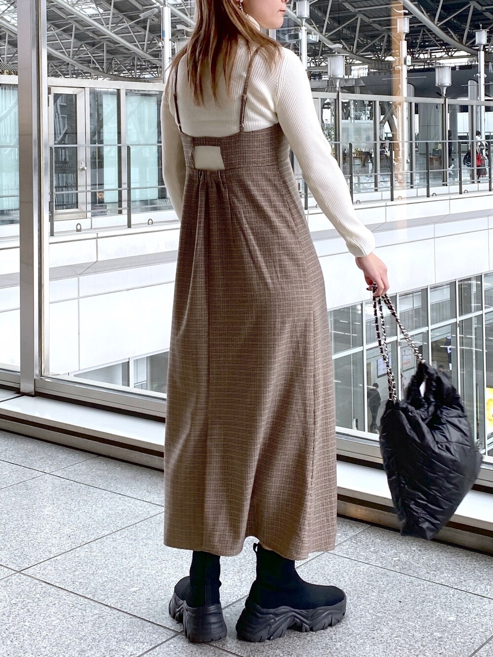 ベージュ系のワンピース、ホワイト系のニット/セーター、ブラック系のトートバッグを着用したレディースの冬コーディネートの2枚目の写真