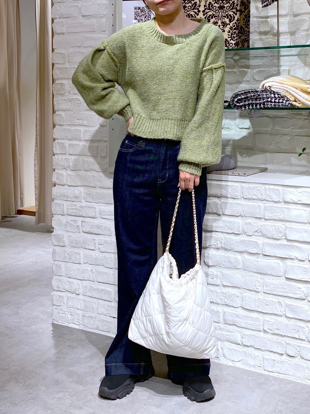 グリーン系のニット/セーター、ブルー系のデニムパンツを着用したレディースの秋コーディネートの2枚目の写真