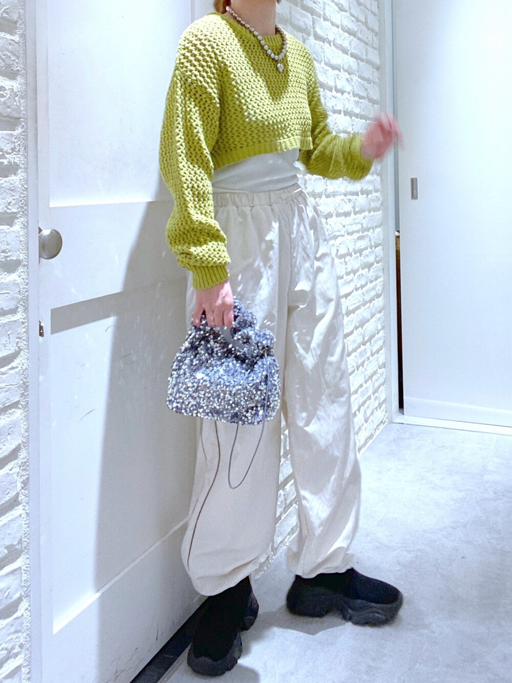 ブラック系のブーツ、グリーン系のニット/セーター、ホワイト系のその他パンツを着用したレディースの春コーディネートの2枚目の写真