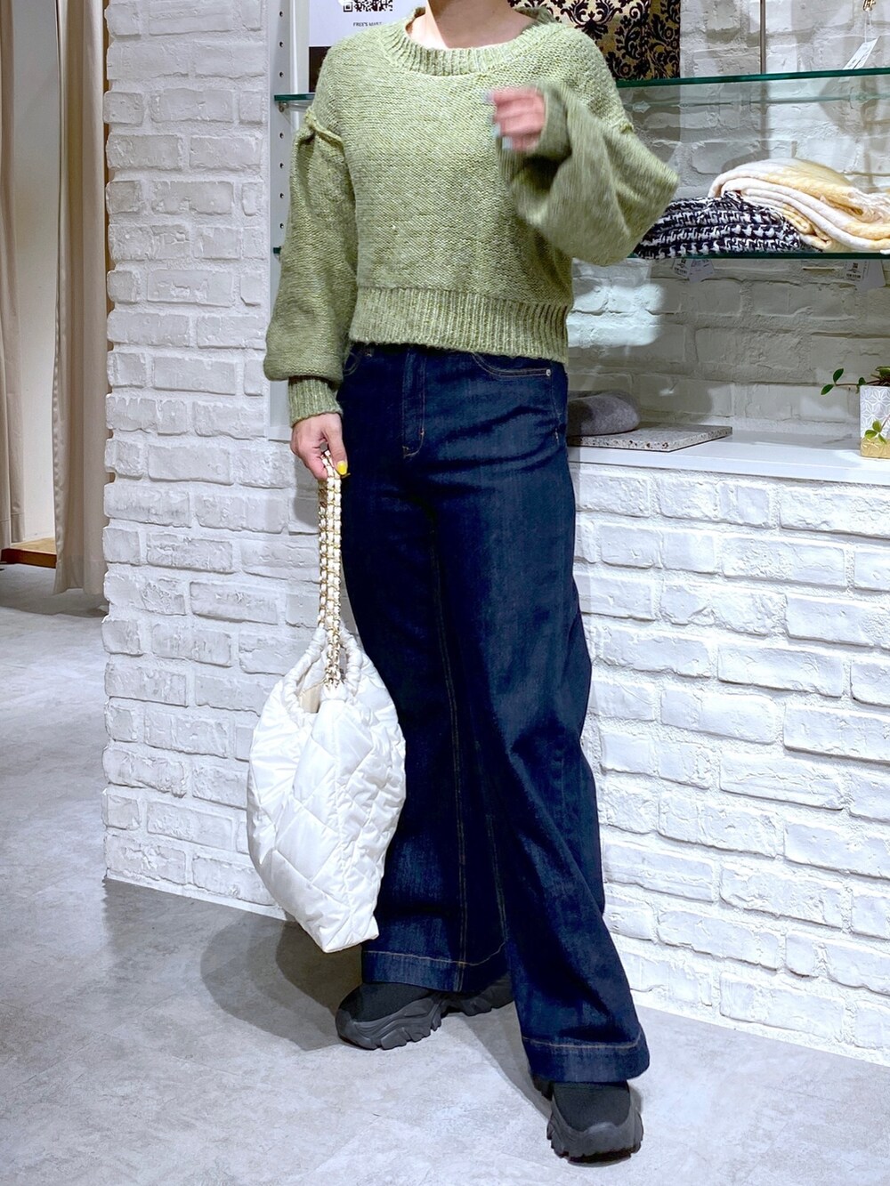 グリーン系のニット/セーター、ブルー系のデニムパンツを着用したレディースの秋コーディネートの3枚目の写真