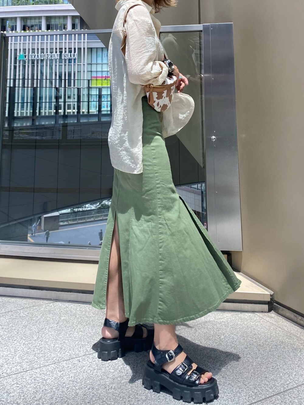 ブラウン系のショルダーバッグ、グリーン系のデニムスカート、ホワイト系のシャツ/ブラウスを着用したレディースの夏コーディネートの3枚目の写真