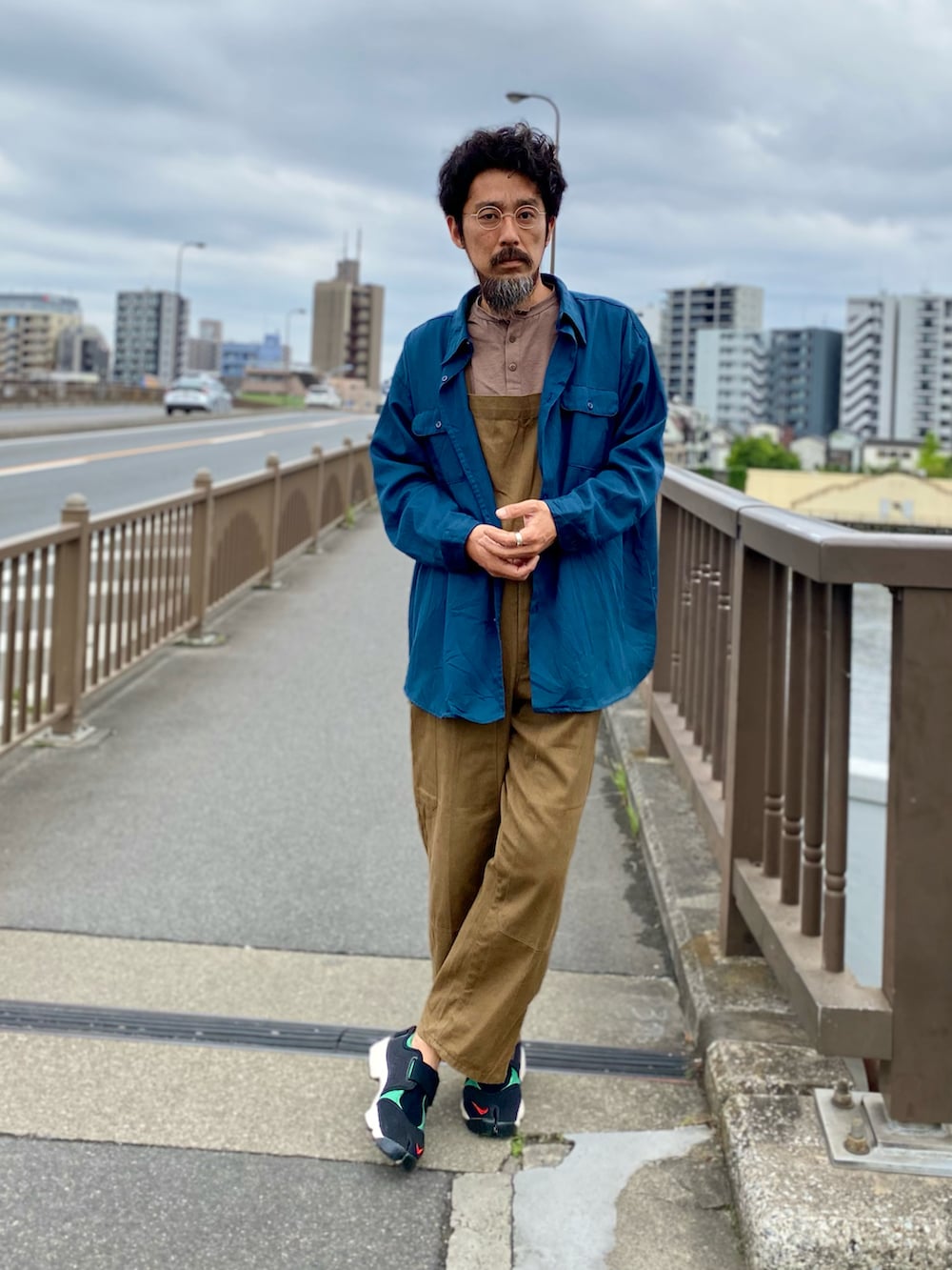 ブラウン系のサロペット/オーバーオール、グリーン系のスニーカー、ブルー系のシャツ/ブラウスを着用したメンズの春コーディネートの2枚目の写真