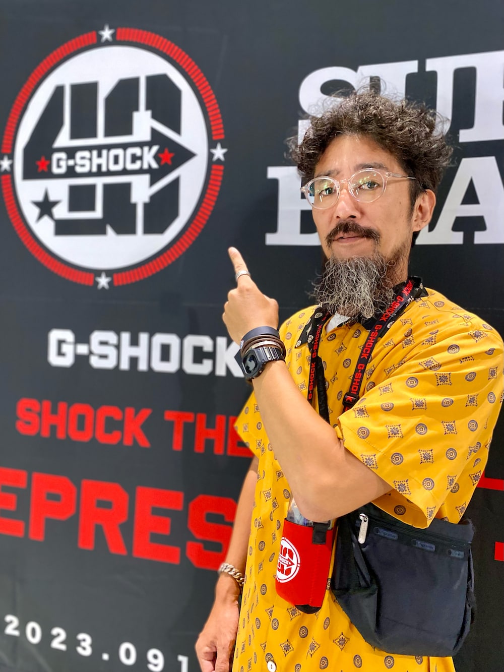 ベージュ系のスラックス、ブラック系のスニーカー、ブラック系のショルダーバッグを着用したメンズの秋コーディネートの2枚目の写真