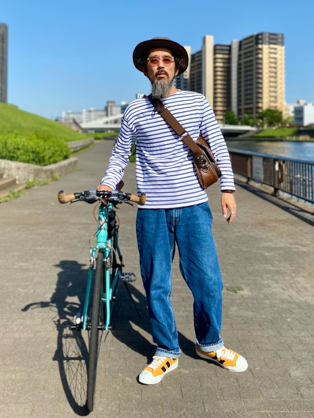 ブルー系のデニムパンツ、イエロー系のスニーカー、ホワイト系のTシャツ/カットソーを着用したメンズの春コーディネートの2枚目の写真