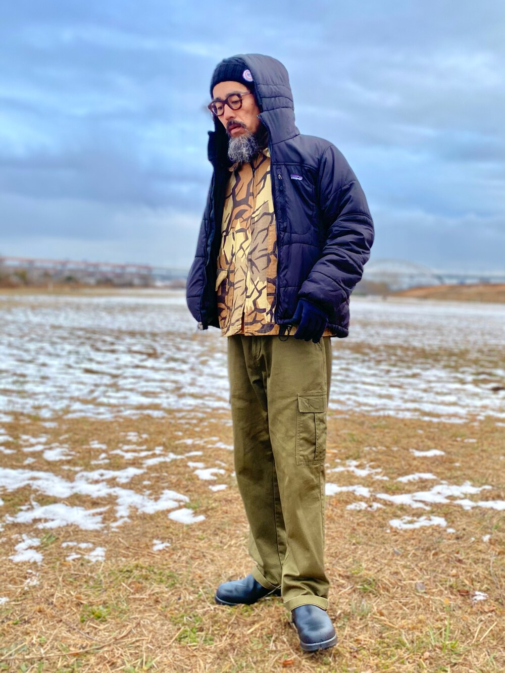 「patagonia、ダウンジャケット、カモフラ、迷彩、タートルネック、カーゴパンツ、ブーツ、ニット帽、アメカジ、古着MIX、アウトドアスタイル、休日スタイル、レイヤードスタイル、メガネ男子、ヴィンテージ」｜「SAINT JAMESのアイテム（ニットキャップ/ビーニー、ブラック系）」を使った、ヤギハシカズヒロさん（メンズ・181cm）の冬コーディネートの2枚目の写真