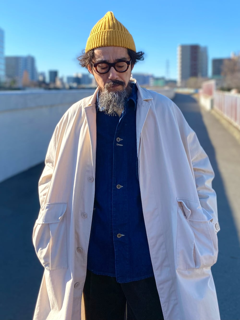 「コート、ロングコート、デニム、カバーオール、スニーカー、ニット帽、レイヤードスタイル、アメカジ、古着MIX、休日スタイル、冬コーデ、お出かけコーデ、冬アウター、ビッグシルエット、大人カジュアル」｜「UNIQLOのアイテム（ニットキャップ/ビーニー、イエロー系）」を使った、ヤギハシカズヒロさん（メンズ・181cm）の冬コーディネートの2枚目の写真