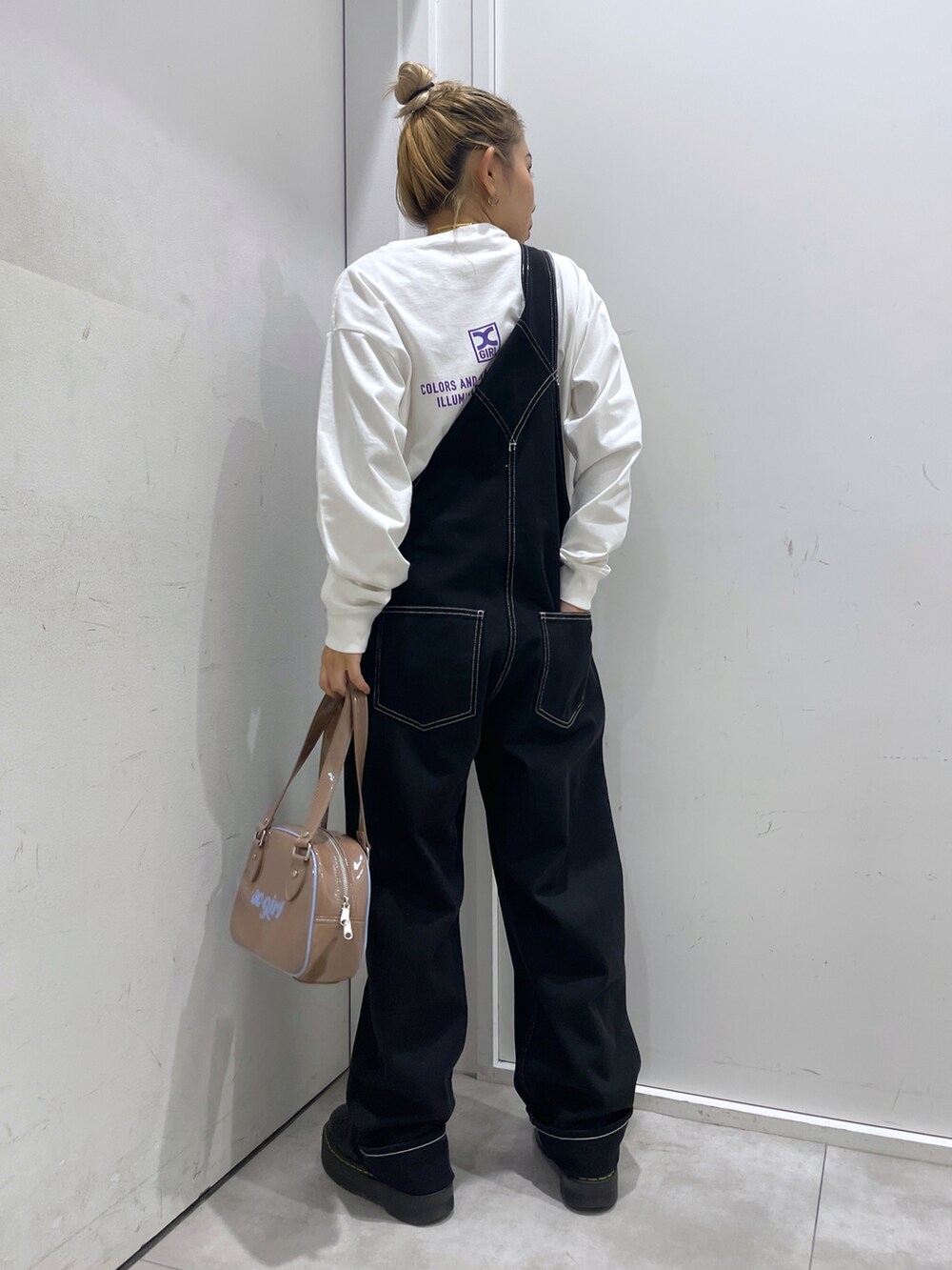 ブラック系のサロペット/オーバーオール、ホワイト系のTシャツ/カットソー、ベージュ系のボストンバッグを着用したレディースの秋コーディネートの2枚目の写真