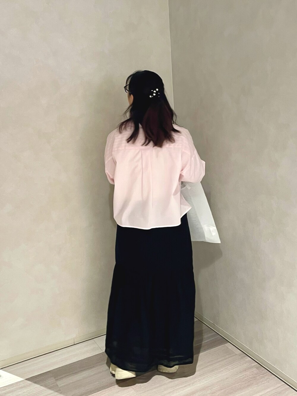ピンク系のシャツ/ブラウス、ブラック系のスカート、ホワイト系のハンドバッグを着用したレディースの春コーディネートの2枚目の写真