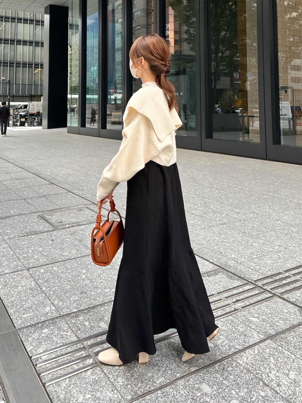 ブラウン系のハンドバッグ、ブラック系のワンピース、ホワイト系のカーディガン/ボレロを着用したレディースの秋コーディネートの2枚目の写真