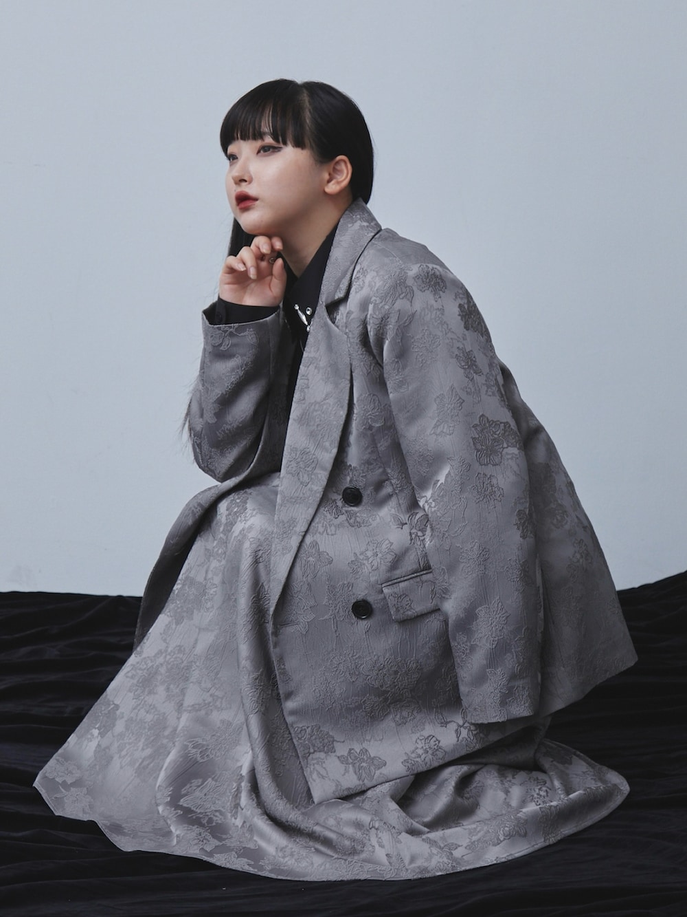 グレー系のテーラードジャケット、グレー系のスカート、ブラック系のシャツ/ブラウスを着用したレディースの秋コーディネートの3枚目の写真