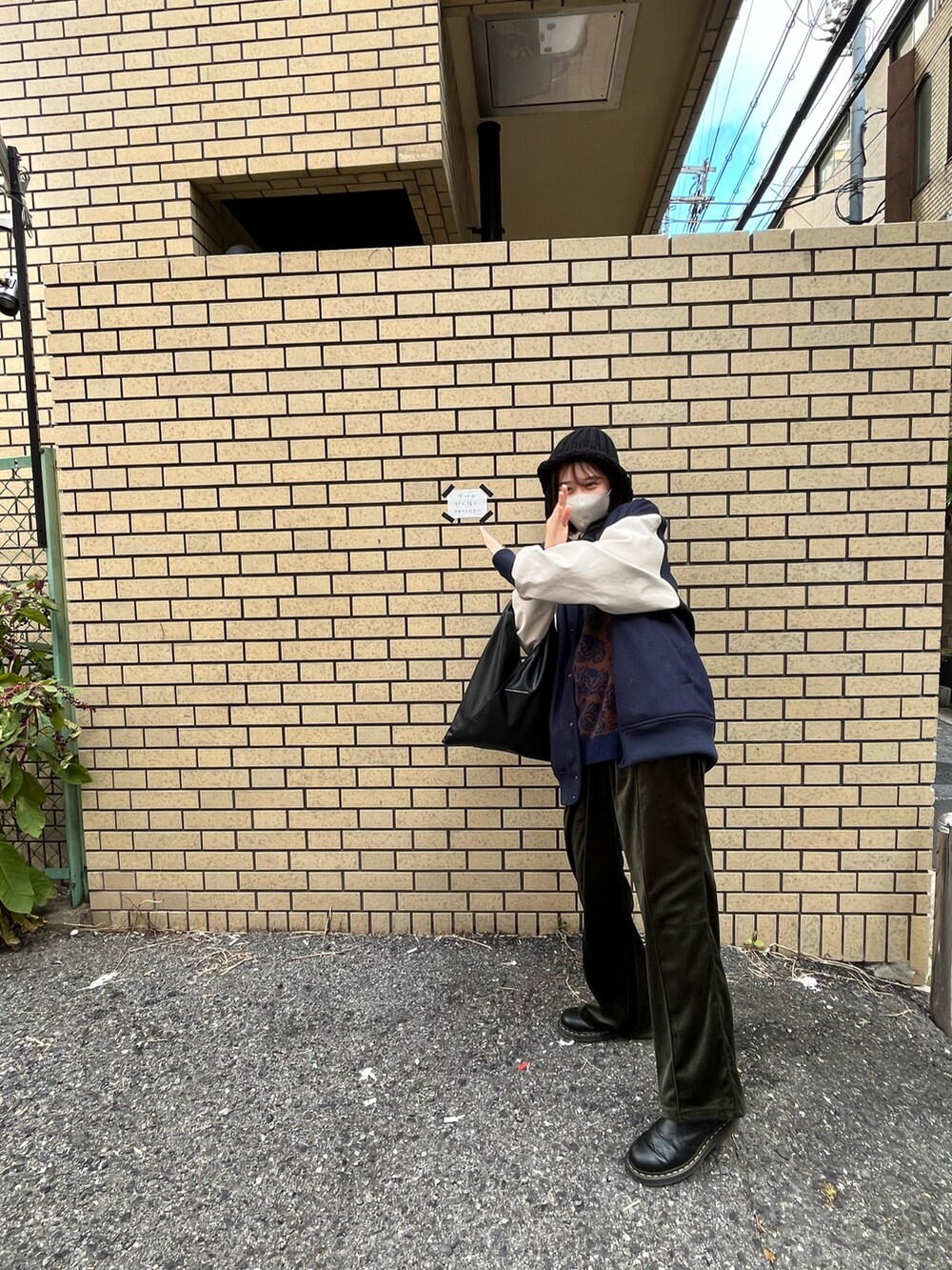 グリーン系のスラックス、ブルー系のスタジャン、ブラック系のハンドバッグを着用したレディースの春コーディネートの2枚目の写真