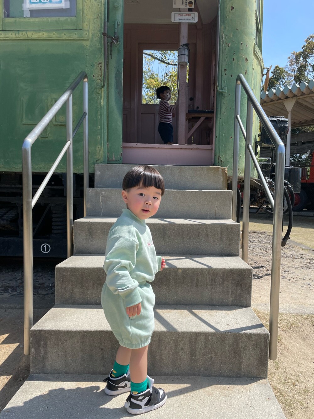 ブルー系のデニムジャケット、グリーン系のトップスを着用したキッズの夏コーディネートの2枚目の写真