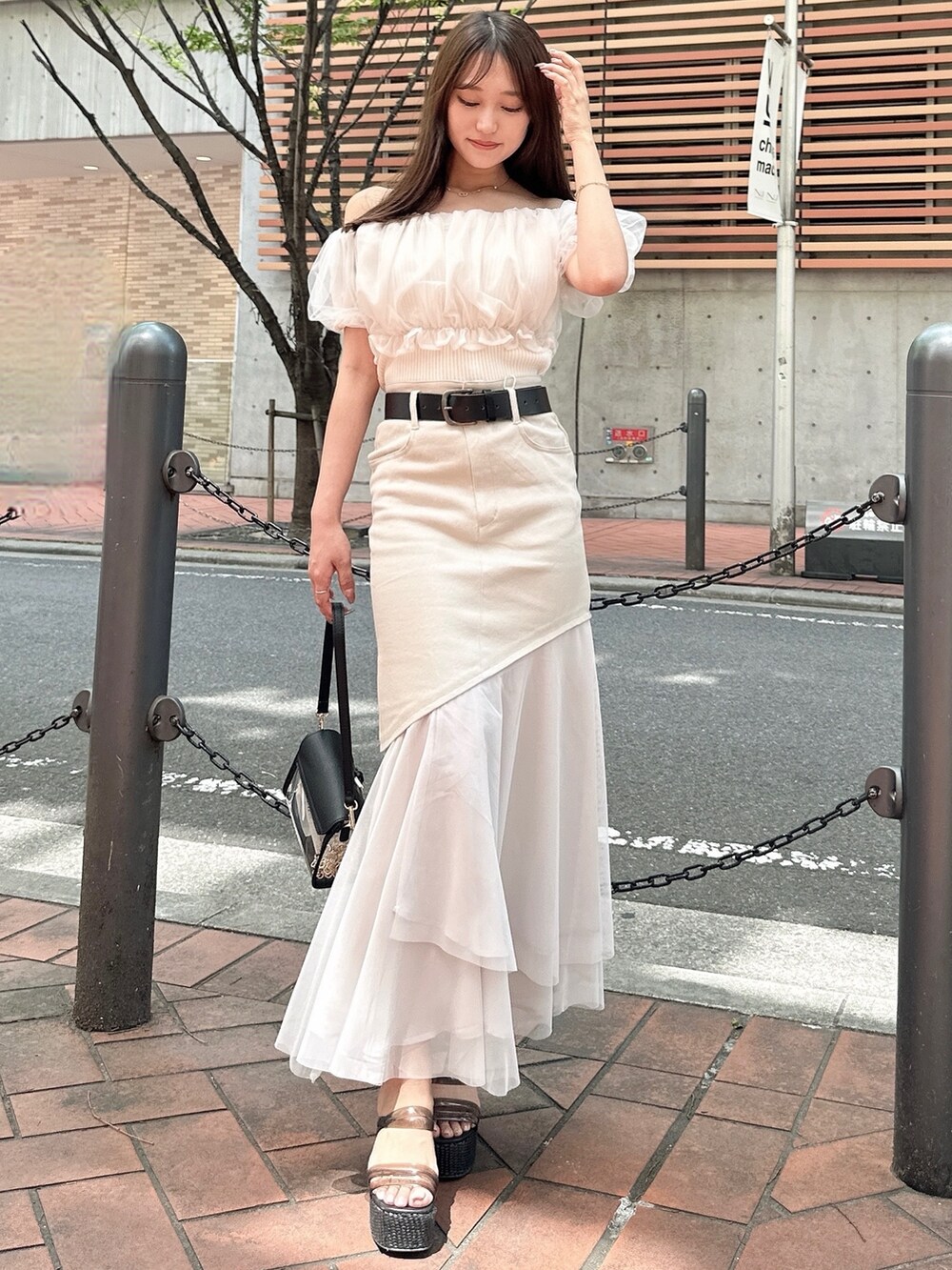 ホワイト系のシャツ/ブラウス、ベージュ系のスカート、ブラック系のハンドバッグを着用したレディースの春コーディネートの2枚目の写真