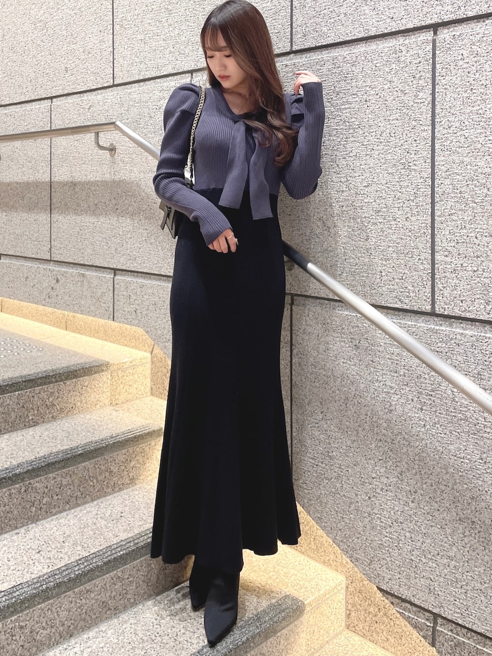 ブルー系のワンピース、ブラック系のブーツ、ブラック系のハンドバッグを着用したレディースの冬コーディネートの2枚目の写真
