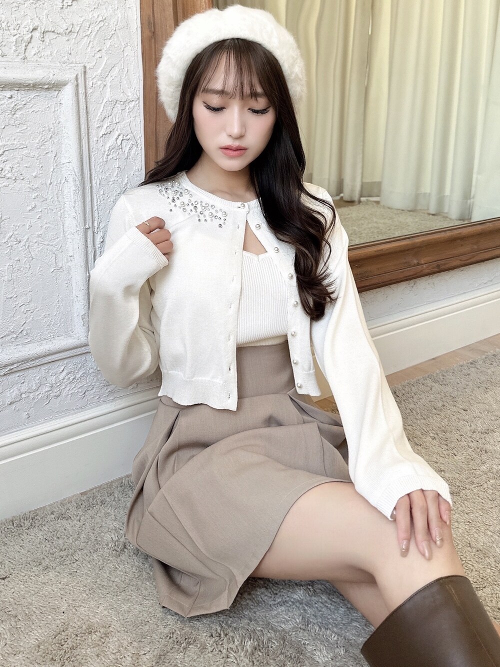 ベージュ系のスカート、ブラック系のブーツ、ホワイト系のハンチング/ベレー帽を着用したレディースの冬コーディネートの2枚目の写真