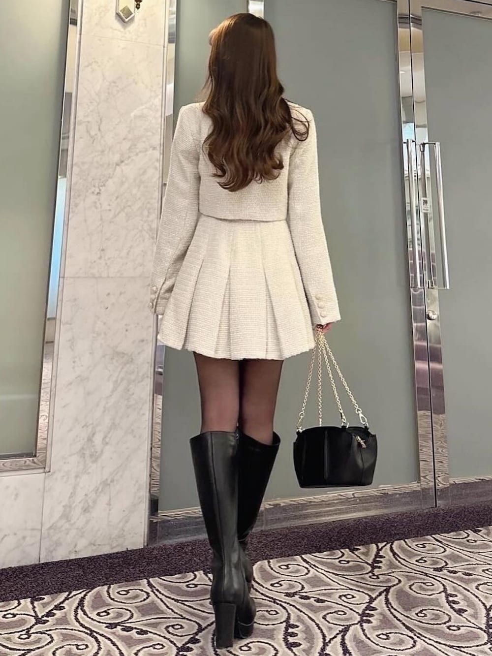 ホワイト系のテーラードジャケット、ホワイト系のスカート、ブラック系のニット/セーターを着用したレディースの春コーディネートの2枚目の写真