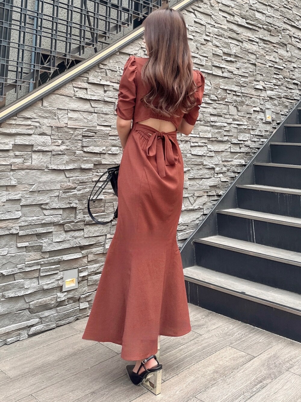 ブラウン系のワンピース、ブラック系のハンドバッグを着用したレディースの夏コーディネートの2枚目の写真