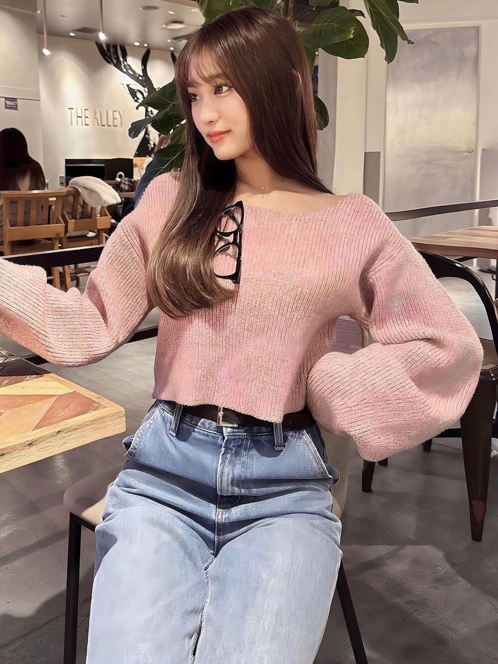 ピンク系のニット/セーター、ブルー系のデニムパンツ、ブラック系のハンドバッグを着用したレディースの冬コーディネートの2枚目の写真