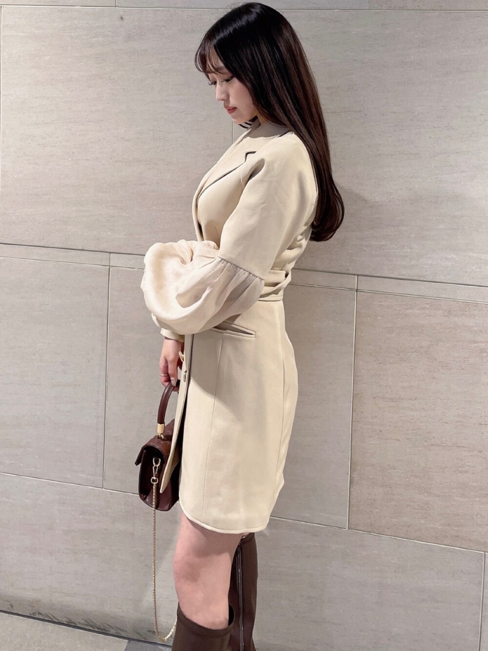 イエロー系のワンピース、ブラウン系のハンドバッグを着用したレディースの冬コーディネートの2枚目の写真