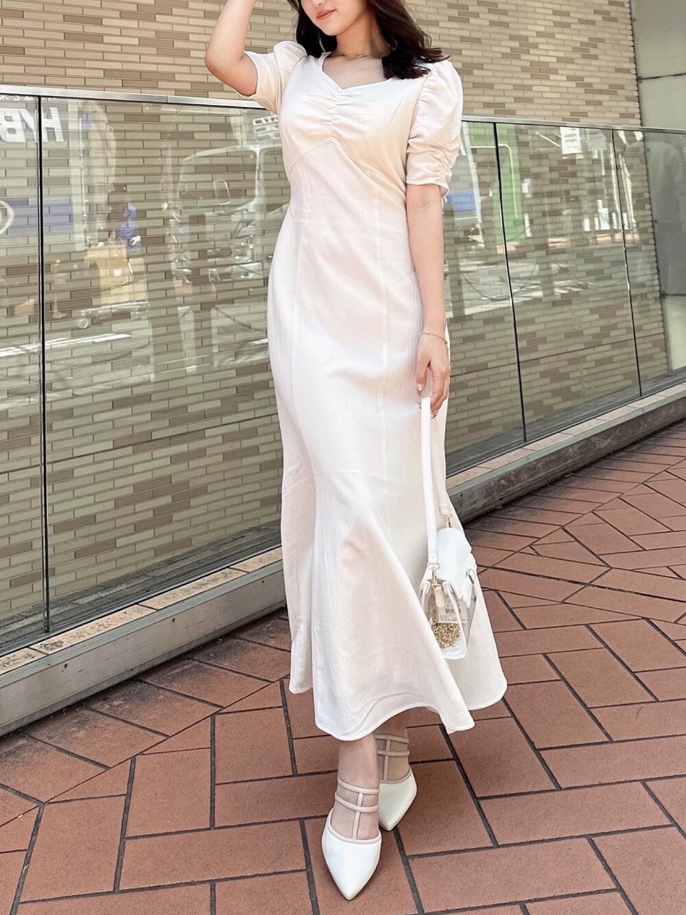 ホワイト系のワンピース、ブラック系のハンドバッグ、ホワイト系のパンプスを着用したレディースの春コーディネートの2枚目の写真