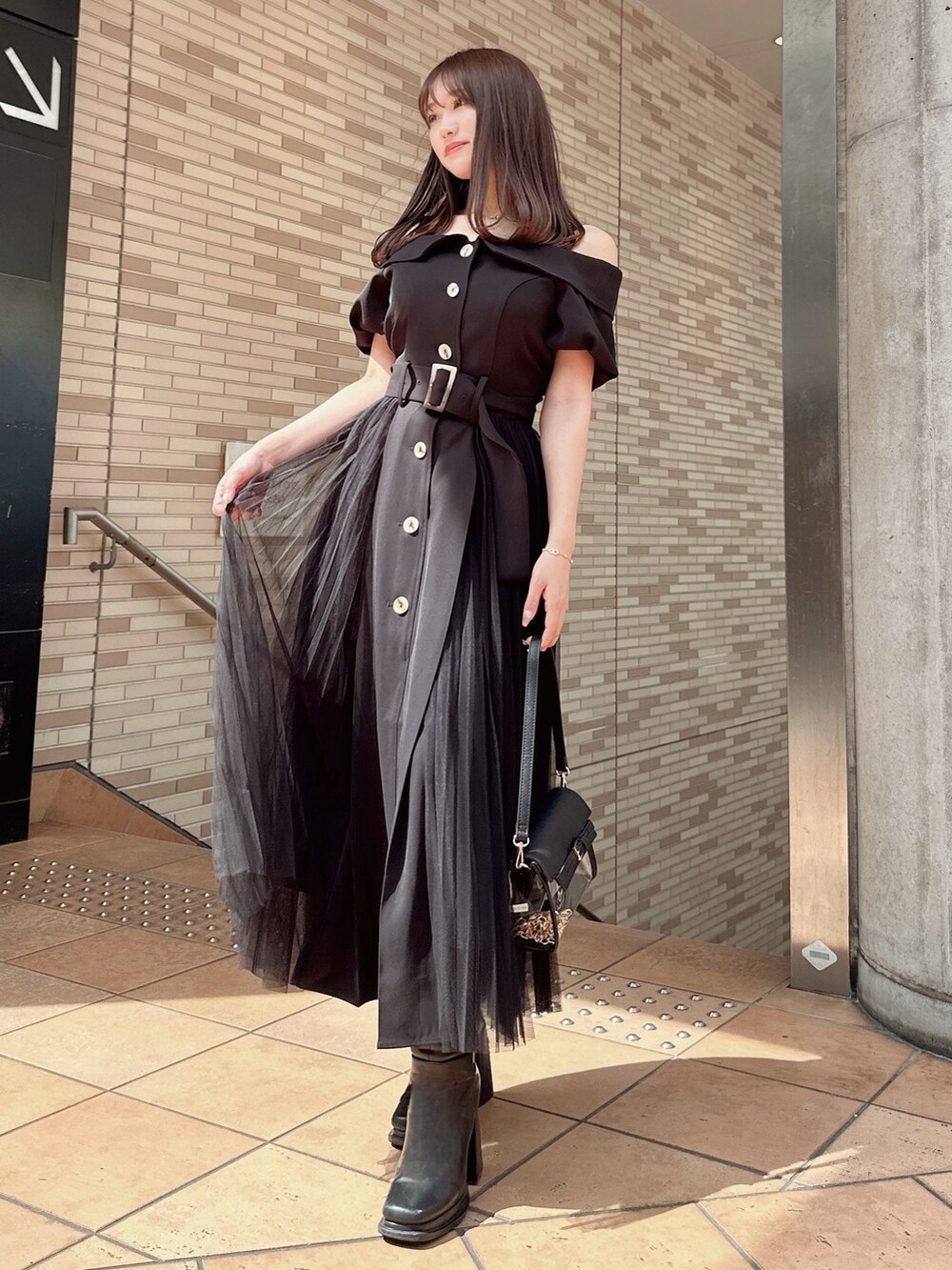 ブラック系のワンピース、ブラック系のハンドバッグを着用したレディースの春コーディネートの2枚目の写真