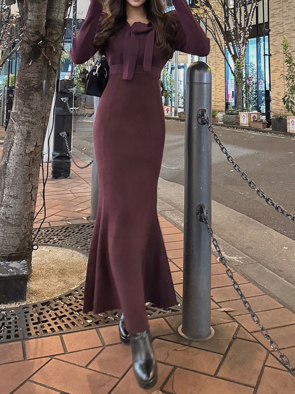 レッド系のワンピース、ブラック系のショルダーバッグ、ブラック系のブーツを着用したレディースの秋コーディネートの3枚目の写真