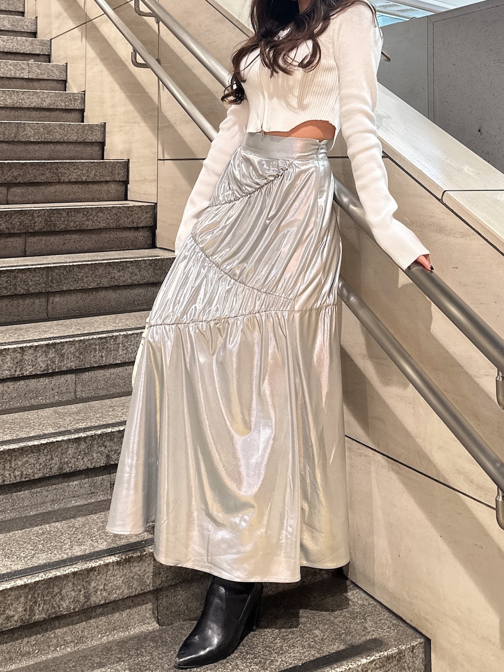 ホワイト系のニット/セーター、シルバー系のスカート、ホワイト系のハンドバッグを着用したレディースの冬コーディネートの2枚目の写真