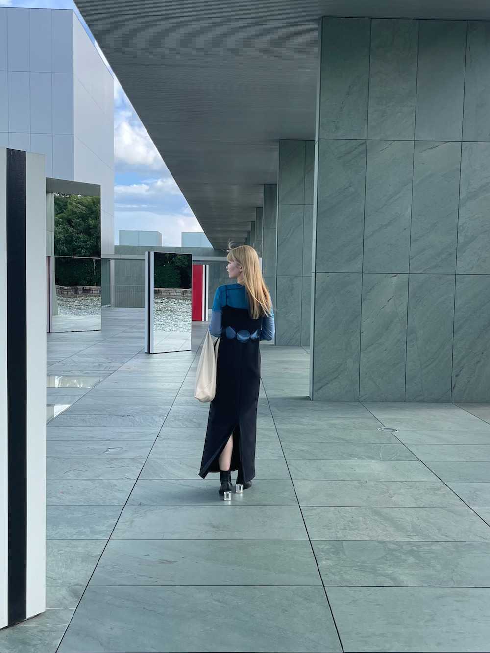 ホワイト系のトートバッグ、ブラック系のワンピース、ブルー系のTシャツ/カットソーを着用したレディースの冬コーディネートの2枚目の写真