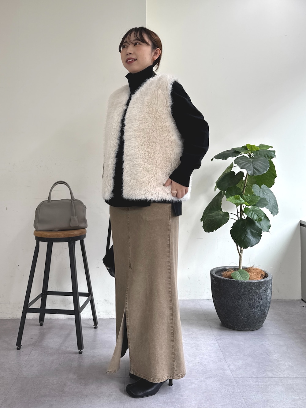 ブラック系のニット/セーター、グリーン系のスカート、ブラック系のショルダーバッグを着用したレディースの秋コーディネートの2枚目の写真