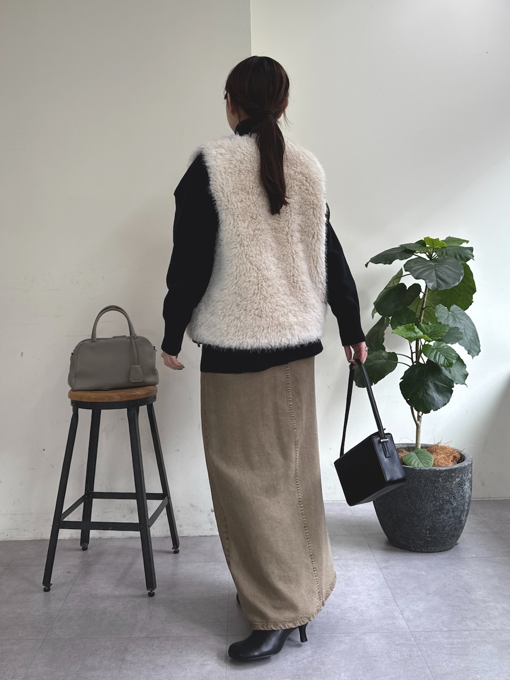 ブラック系のニット/セーター、グリーン系のスカート、ブラック系のショルダーバッグを着用したレディースの秋コーディネートの4枚目の写真