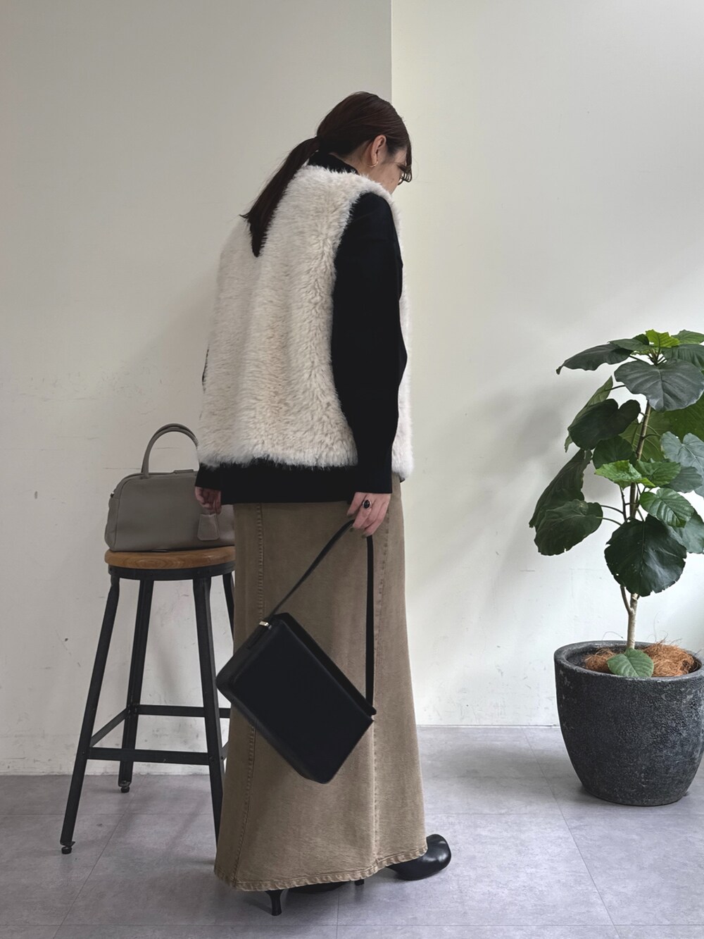 ブラック系のニット/セーター、グリーン系のスカート、ブラック系のショルダーバッグを着用したレディースの秋コーディネートの5枚目の写真