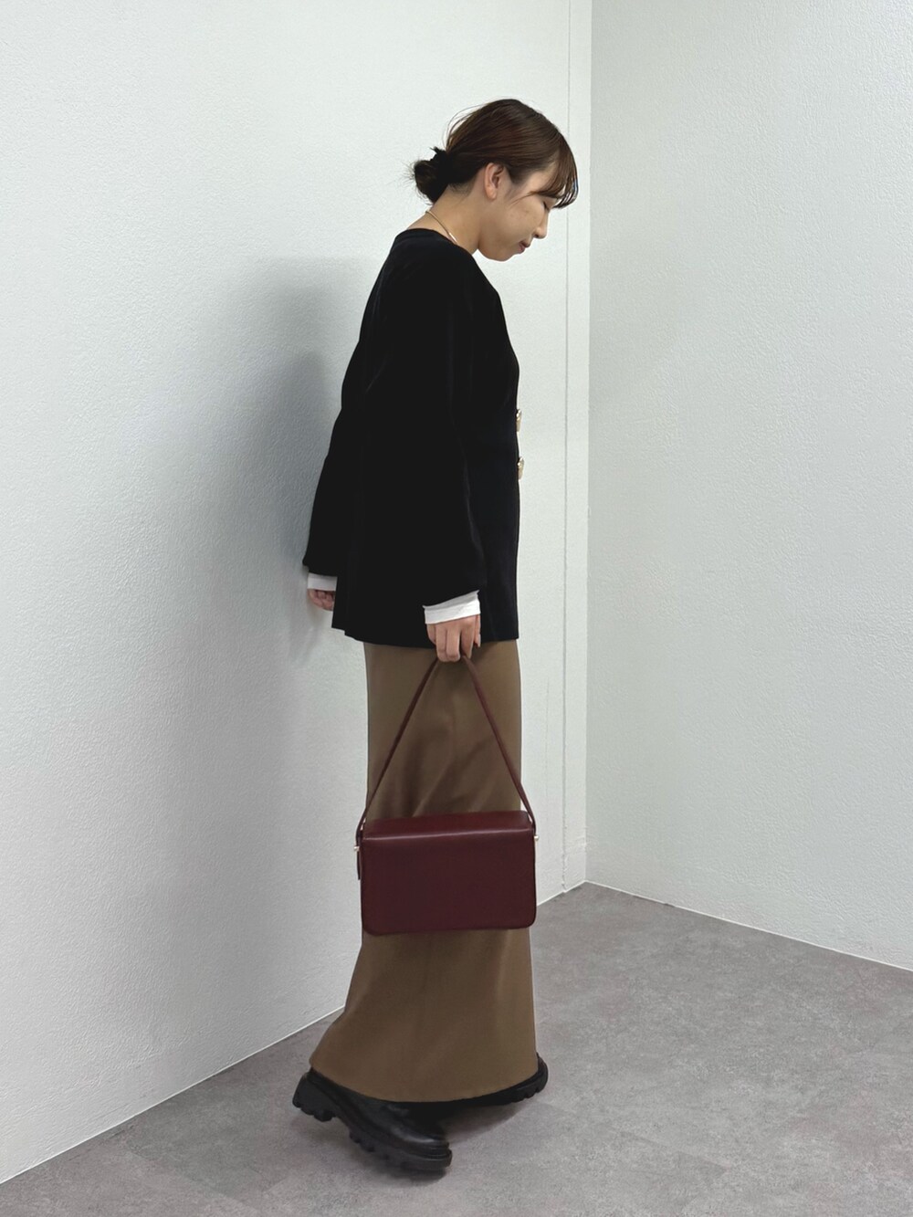 ブラック系のニット/セーター、ブラウン系のスカート、ブラック系のブーツを着用したレディースの秋コーディネートの2枚目の写真