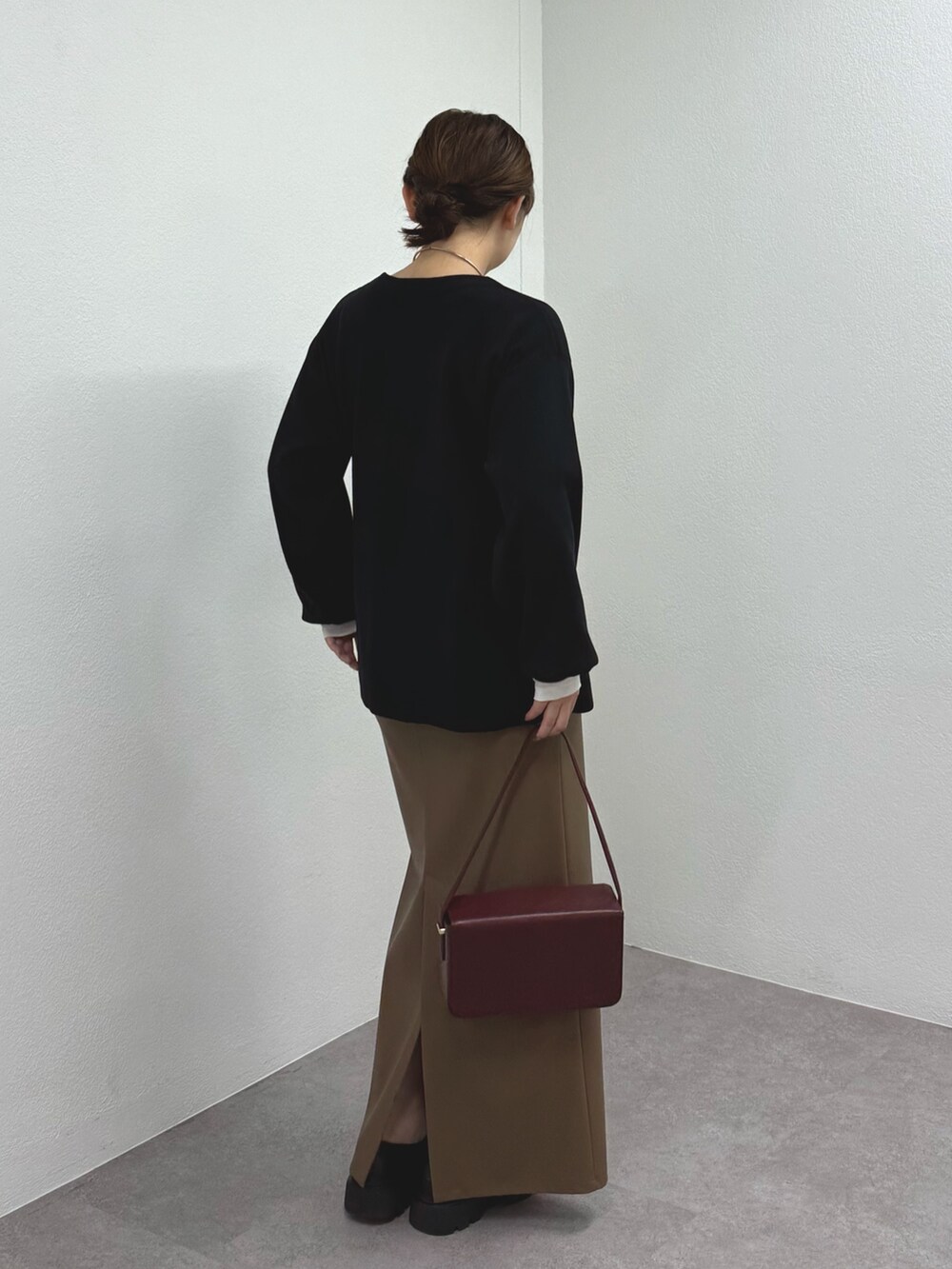 ブラック系のニット/セーター、ブラウン系のスカート、ブラック系のブーツを着用したレディースの秋コーディネートの3枚目の写真