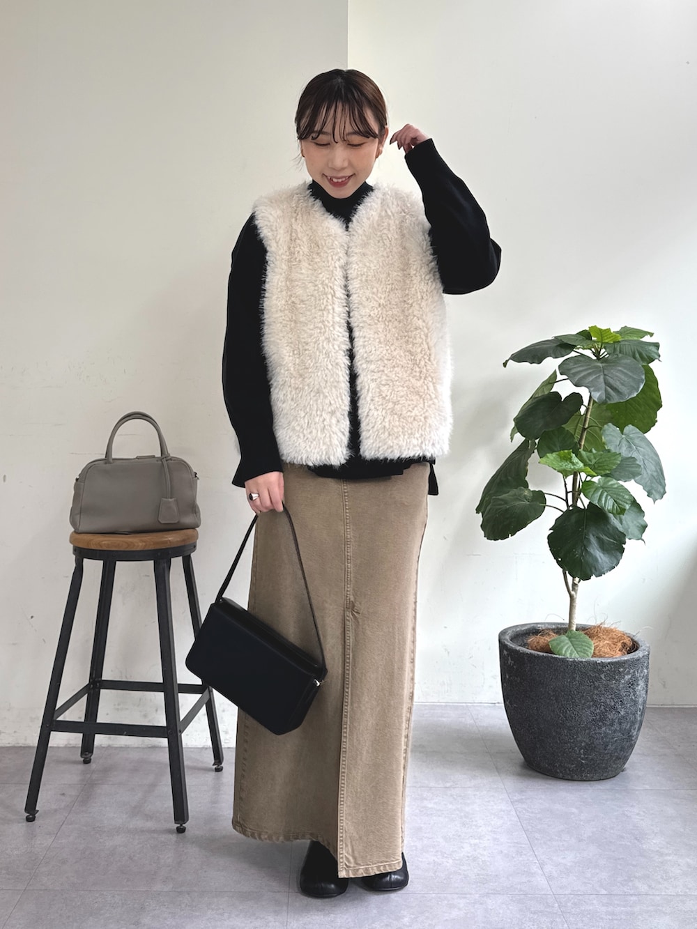 ブラック系のニット/セーター、グリーン系のスカート、ブラック系のショルダーバッグを着用したレディースの秋コーディネートの3枚目の写真