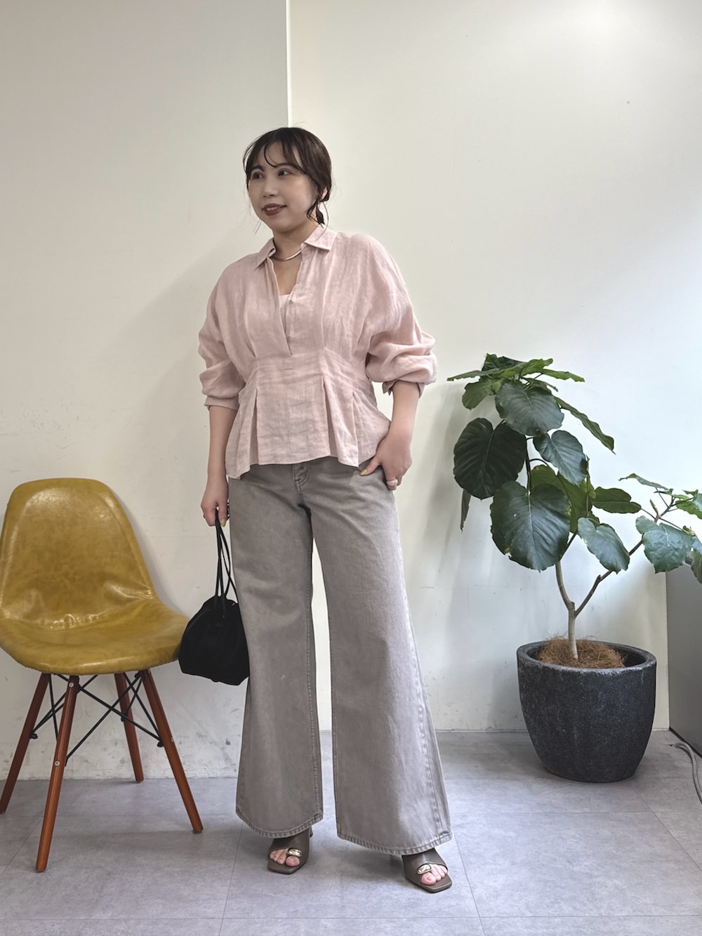 ブラウン系のデニムパンツ、ブラック系のトートバッグ、ブラウン系のサンダルを着用したレディースの春コーディネートの2枚目の写真