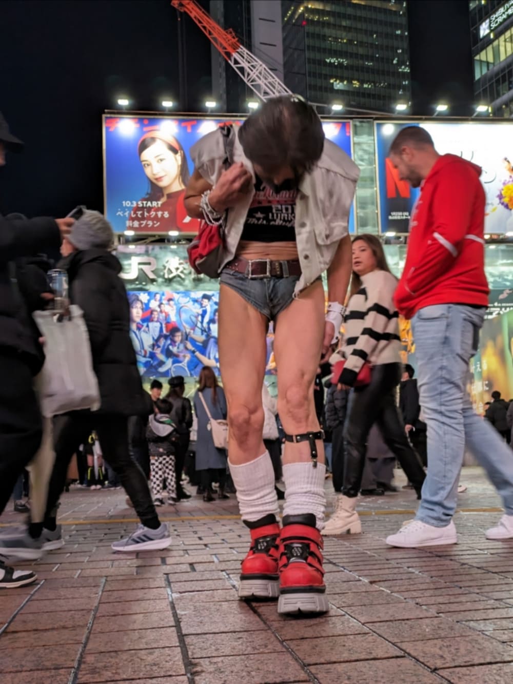 レッド系のスニーカー、ホワイト系のベスト、ブラック系のタンクトップを着用したメンズの冬コーディネートの5枚目の写真