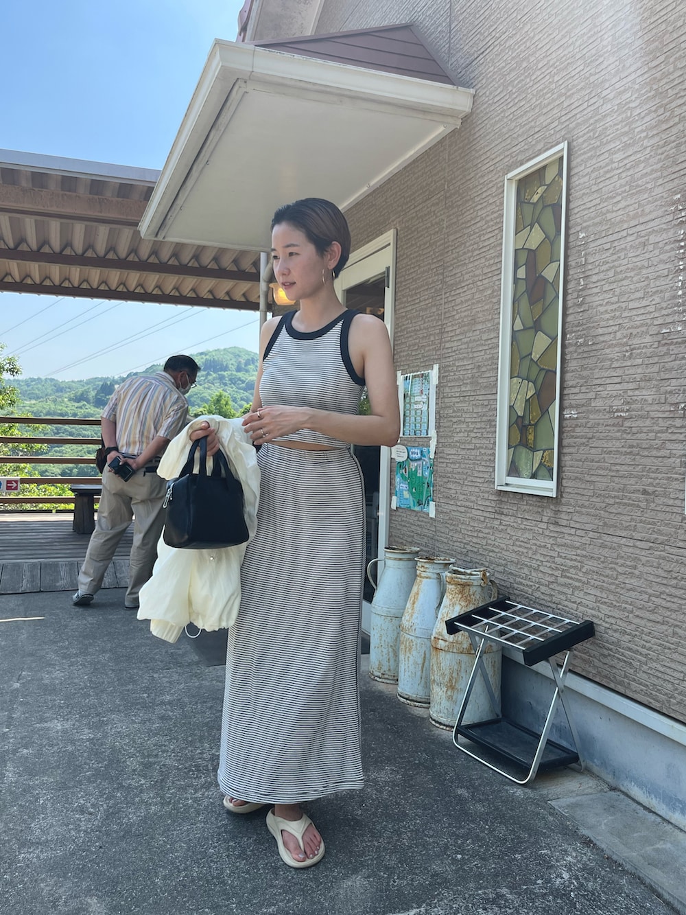 ブルー系のスカート、ブルー系のタンクトップ、ホワイト系のブルゾンを着用したレディースの春コーディネートの2枚目の写真