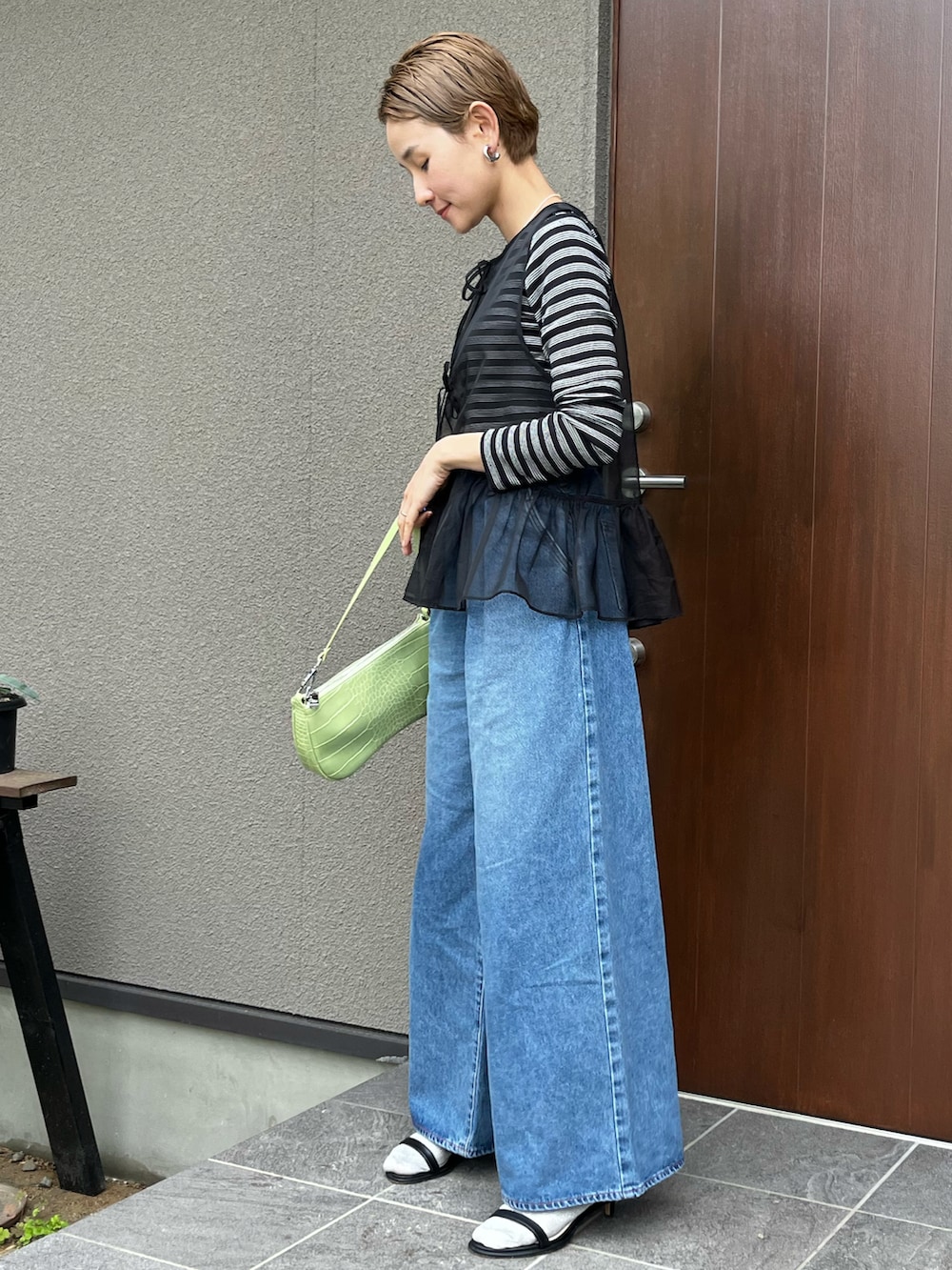 ブラック系のベスト、ブラック系のTシャツ/カットソー、ブルー系のデニムパンツを着用したレディースの春コーディネートの2枚目の写真