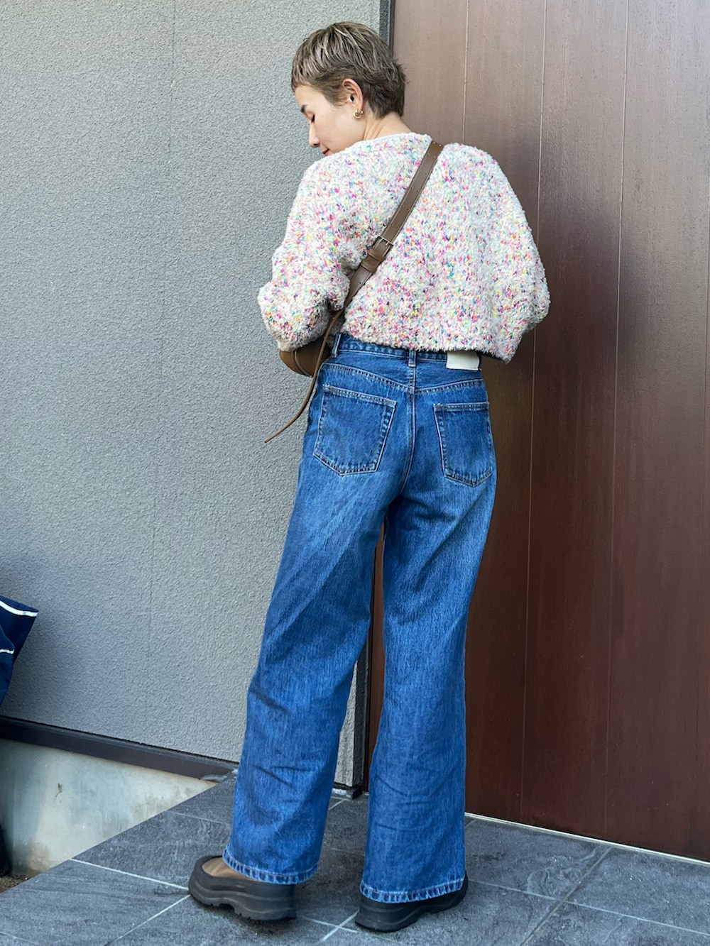 ブラウン系のショルダーバッグ、ベージュ系のニット/セーター、ブルー系のデニムパンツを着用したレディースの秋コーディネートの3枚目の写真