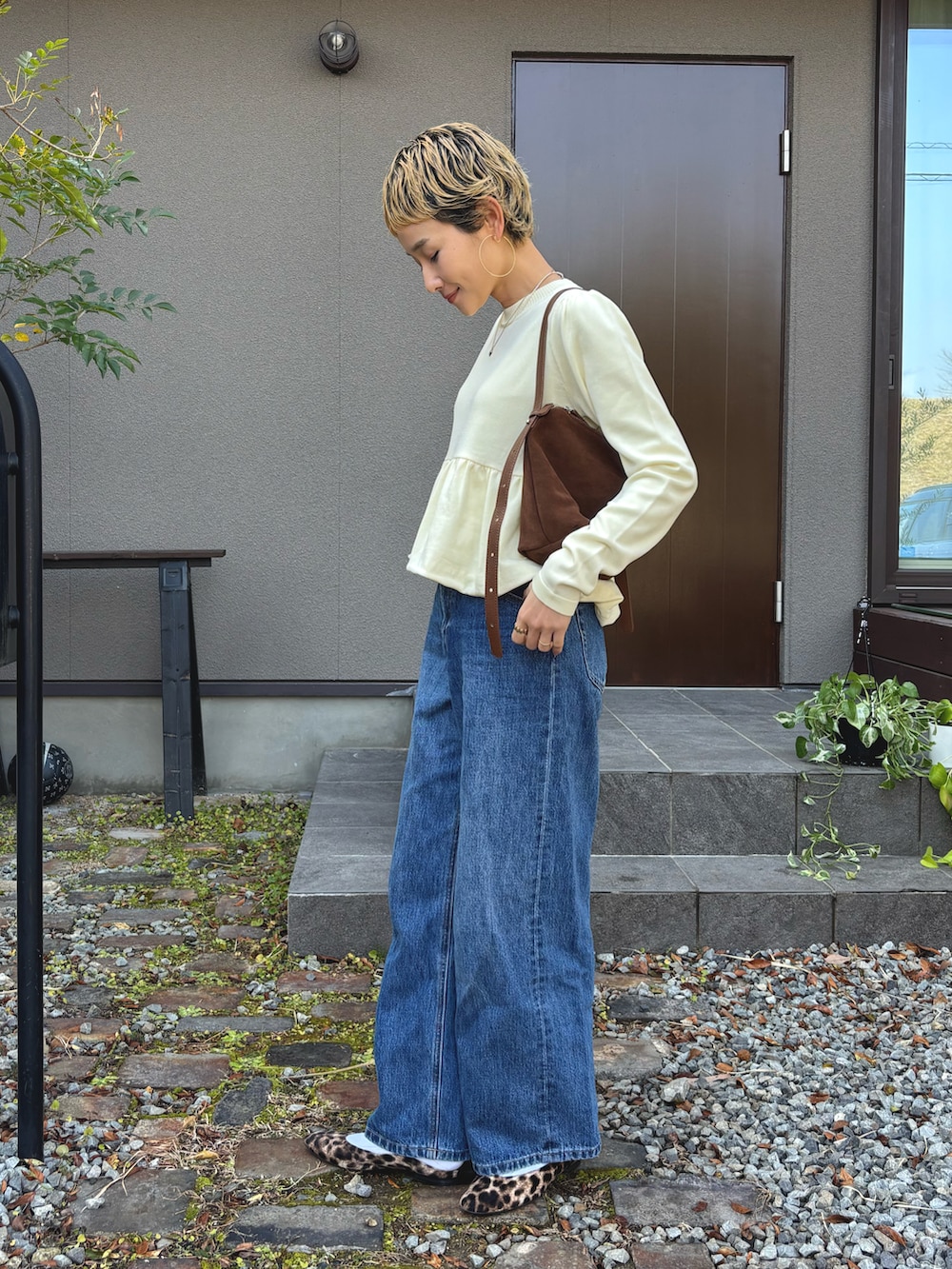 イエロー系のニット/セーター、ブラウン系のショルダーバッグ、ブルー系のデニムパンツを着用したレディースの冬コーディネートの2枚目の写真