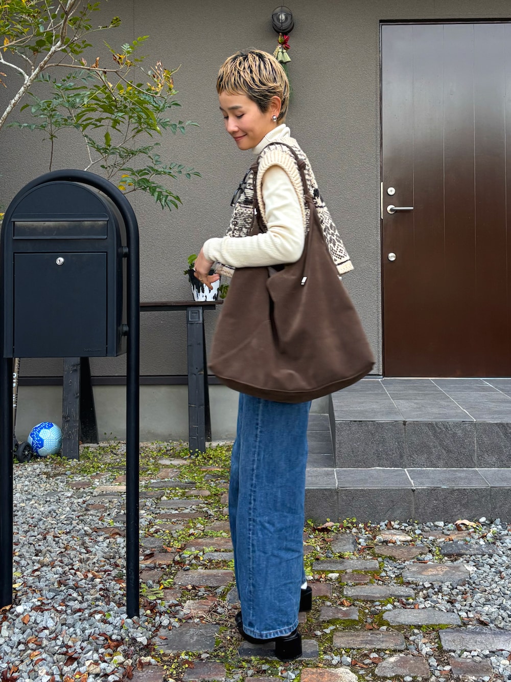 ホワイト系のニット/セーター、ベージュ系のベスト、グリーン系のショルダーバッグを着用したレディースの冬コーディネートの2枚目の写真