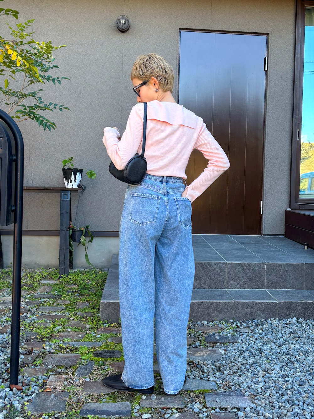 ピンク系のカーディガン/ボレロ、ブラック系のハンドバッグ、ブルー系のデニムパンツを着用したレディースの秋コーディネートの3枚目の写真