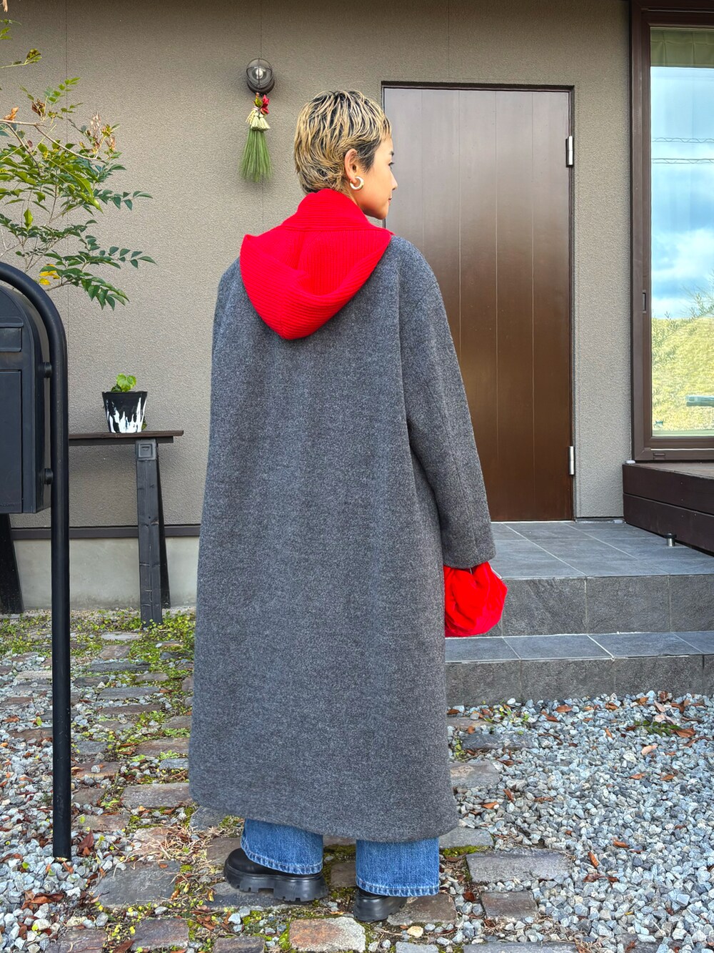 グレー系のステンカラーコート、ブラック系のTシャツ/カットソー、ブラック系のブーツを着用したレディースの冬コーディネートの4枚目の写真