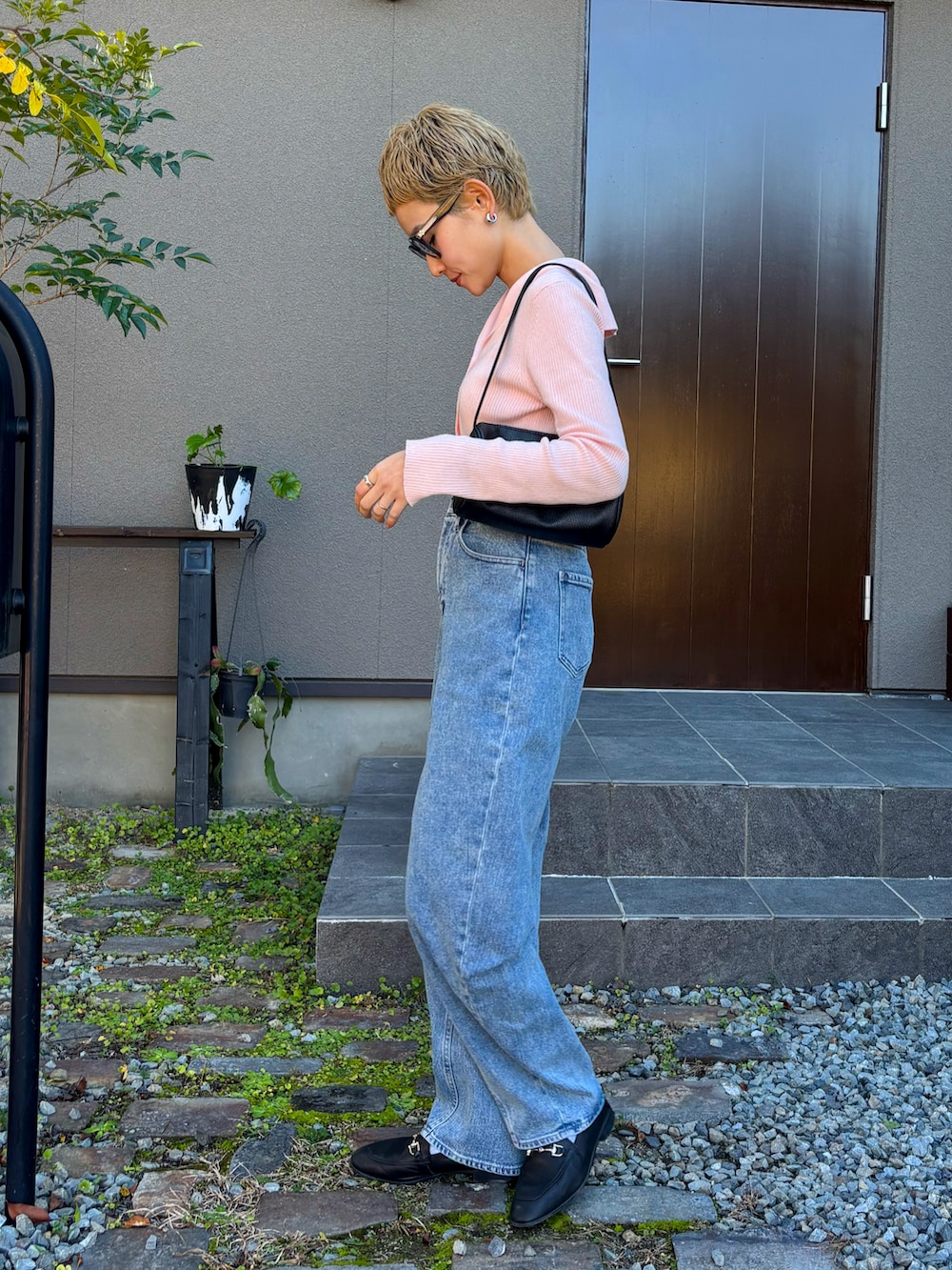 ピンク系のカーディガン/ボレロ、ブラック系のハンドバッグ、ブルー系のデニムパンツを着用したレディースの秋コーディネートの2枚目の写真