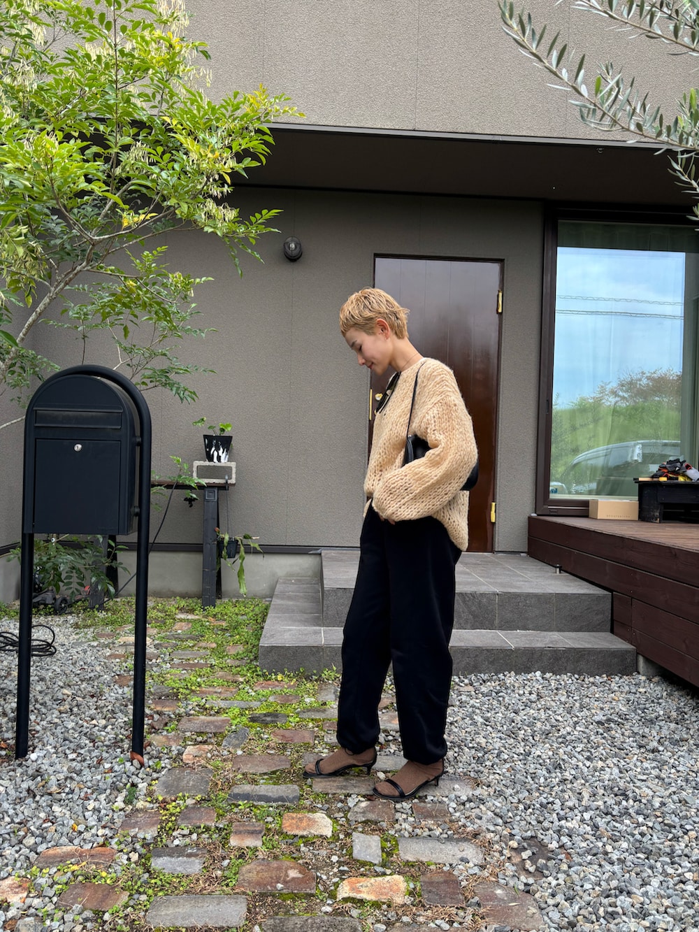 オレンジ系のニット/セーター、ブラック系のその他パンツ、ブラック系のサンダルを着用したレディースの秋コーディネートの2枚目の写真