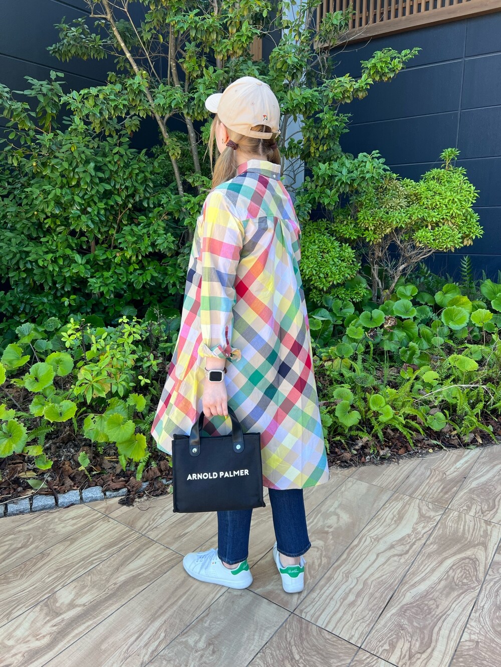 ベージュ系のシャツワンピース、ブルー系のデニムパンツ、グリーン系のスニーカーを着用したレディースの夏コーディネートの2枚目の写真