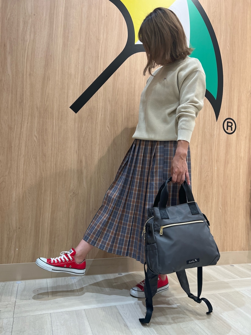 ホワイト系のニット/セーター、グレー系のスカート、グレー系のバックパック/リュックを着用したレディースの秋コーディネートの2枚目の写真